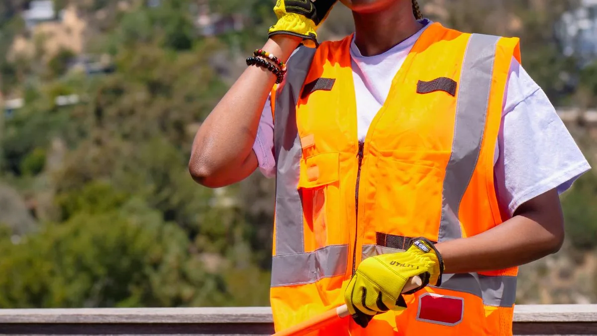 Trained road worker directing traffic beside a construction zone.