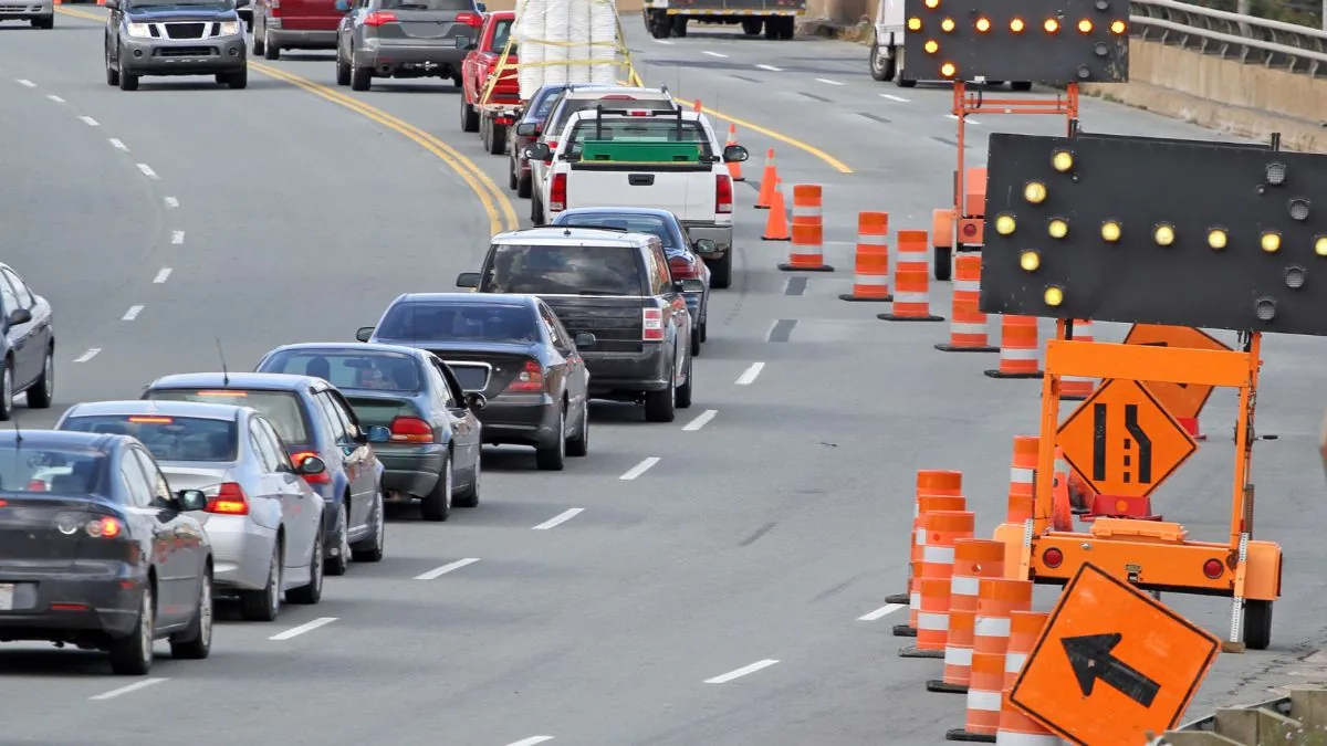 Traffic moving beside an active urban road construction zone.