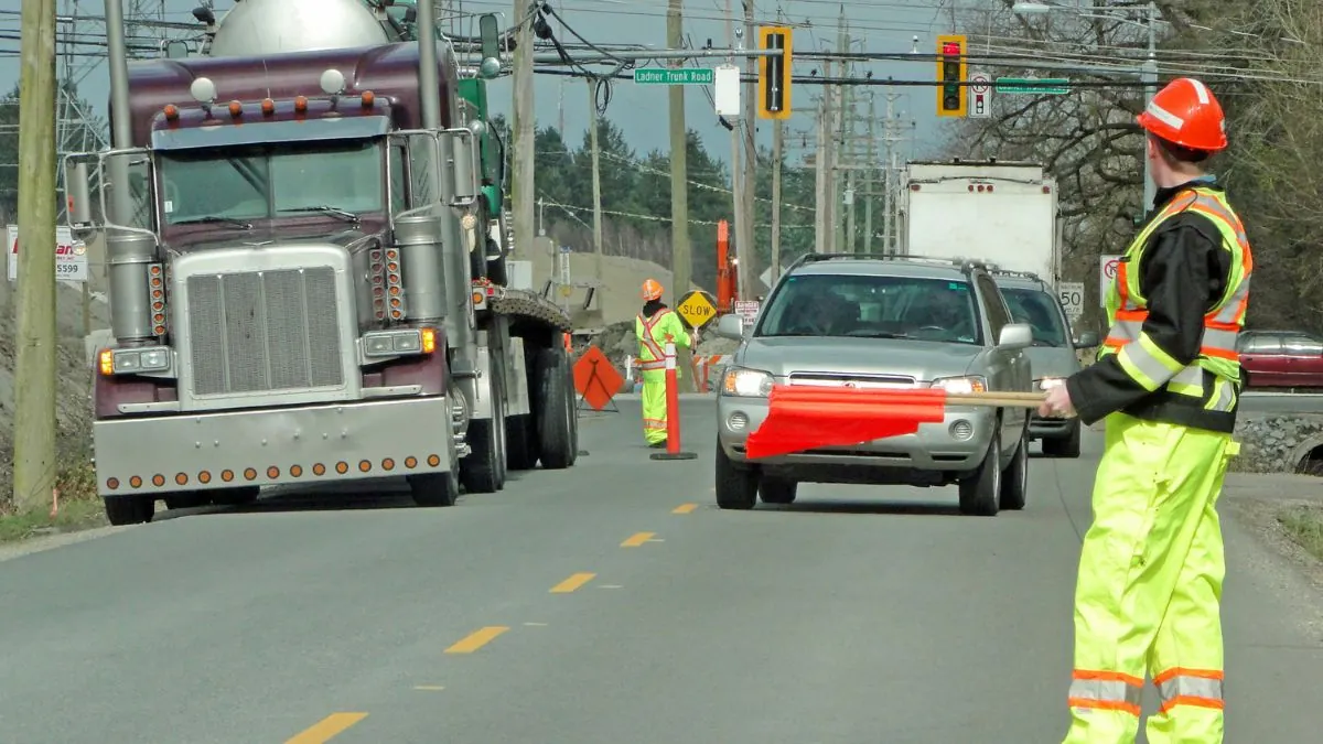 Traffic-control person directing vehicles with a handheld stop sign.